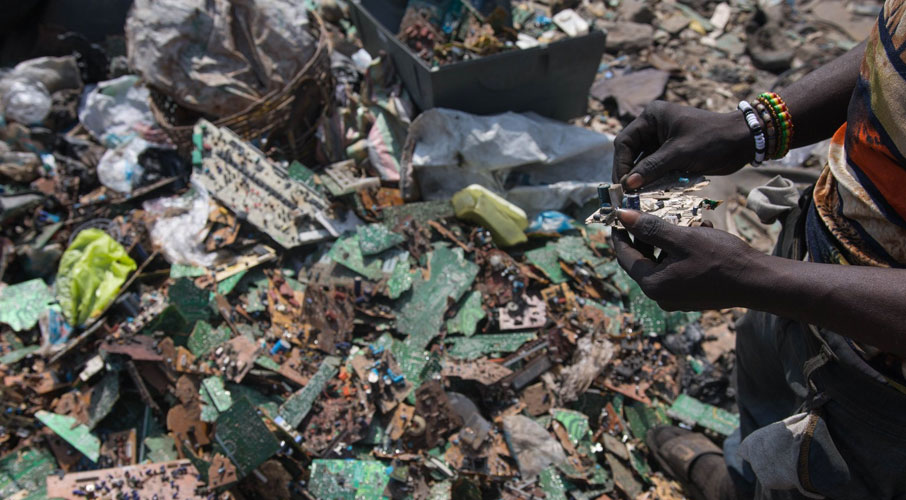 Worker sorting through e-waste at dump site