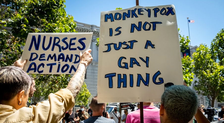 People hold signs during a rally to demand that the federal government respond to the monkeypox outbreak